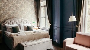 A bedroom with a tufted headboard bed, a matching bench, a pink sofa, and a window with curtains. - Billnäsin ruukki (Raseborg)