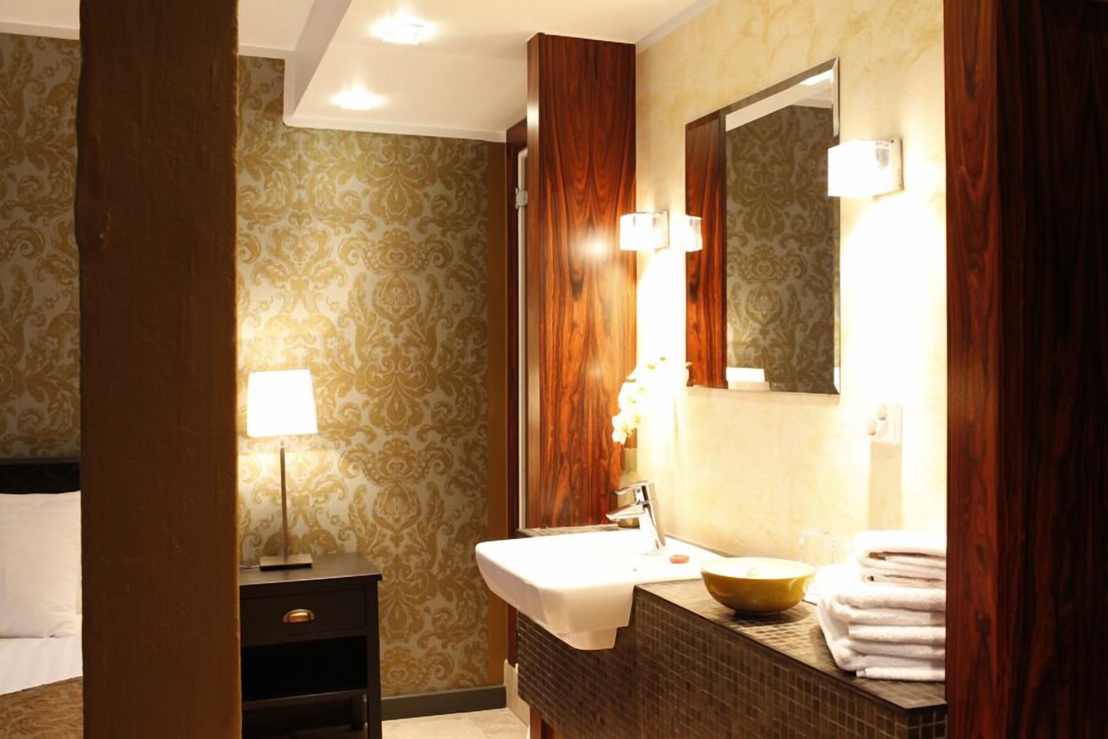 Un baño de hotel con tocador, lavabo, espejo y perchero para toallas.