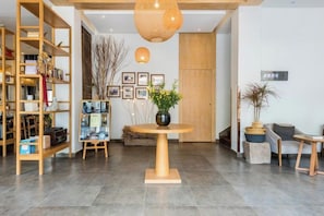 A reception area with a round table, a bookshelf, and a potted plant. - Cili Ciwai Hostel (Jingdezhen)