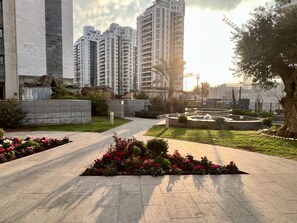 A residential area with modern high-rise buildings, a paved walkway, and landscaped gardens.