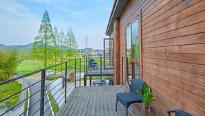 Una terraza de madera con vistas a un paisaje verde y una carretera.