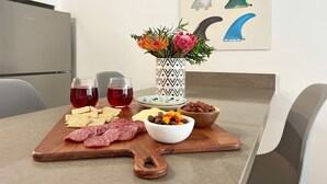 Ein Holzbrett mit Snacks, Getränken und einer Oliven-Schale.