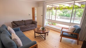 A living room with a brown sofa, a blue sofa, and a wooden coffee table. - 5BR Home w/ Saltwater Pool – Pet Friendly, Near Seacliff Beach & Marion | Ideal for Extended Stays (Seacliff Park)