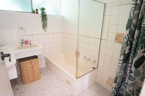 Une salle de bain avec un lavabo blanc, une baignoire et un espace douche.