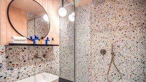 A modern bathroom with a freestanding sink, a glass shower enclosure, and a mirror with a wooden shelf above it. - Sheva Boutique Hotel (Milan)