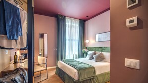 A hotel room with a bed, a chair, a desk with a laptop, a mirror, and a window with curtains. - Sheva Boutique Hotel (Milan)