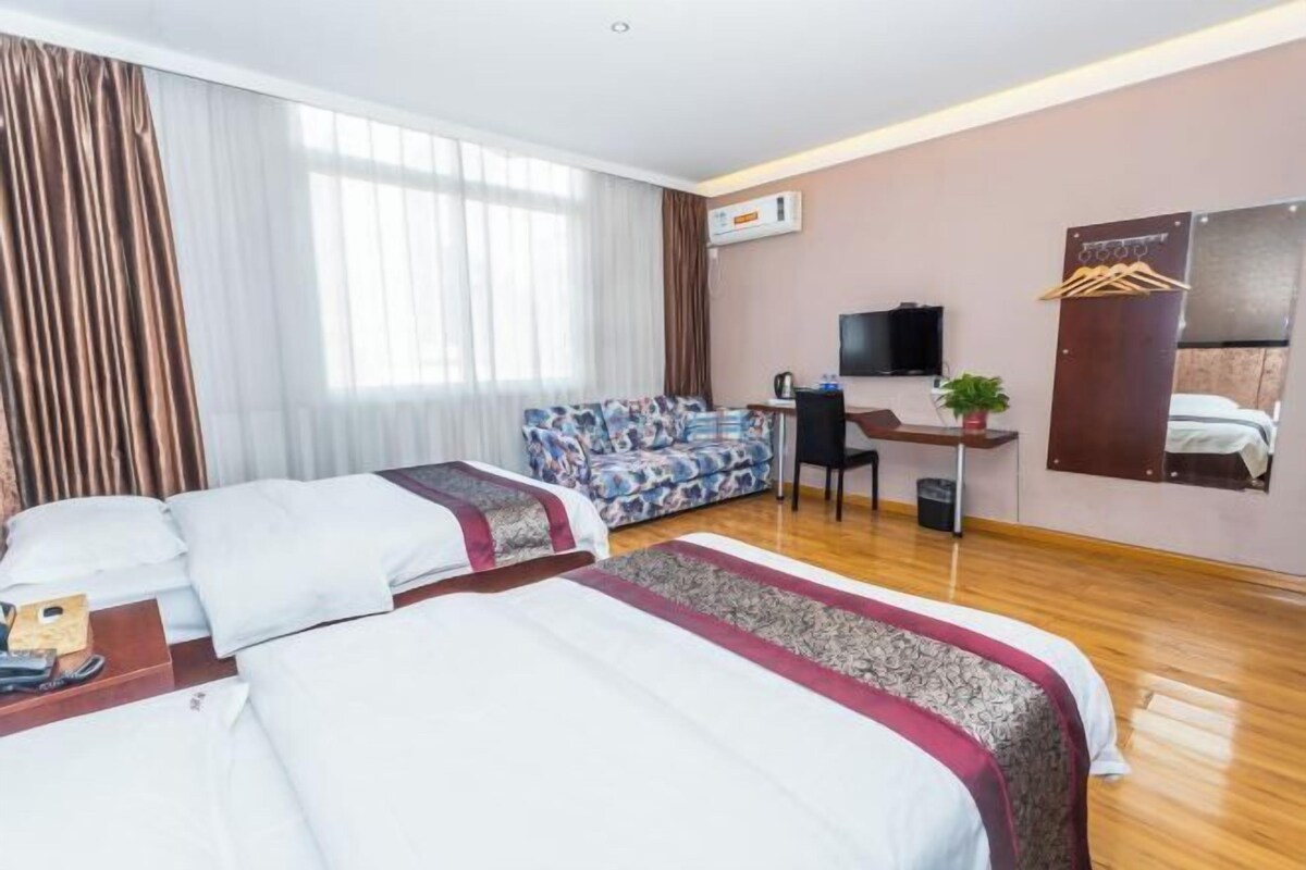 Une chambre d’hôtel avec deux lits, un canapé, un bureau, une télévision et un miroir.