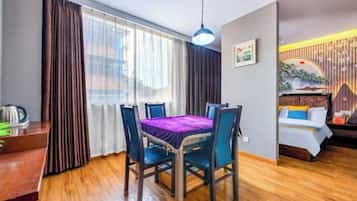 Habitación de hotel con una mesa de comedor, sillas, cama y ventana con cortinas.