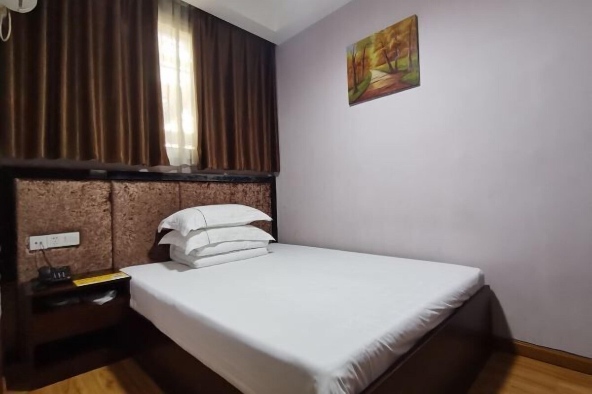 Une chambre d’hôtel avec un lit, une table de chevet, une prise de courant et un tableau au mur.