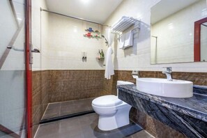 Une salle de bain avec des toilettes blanches, un lavabo et un espace douche.