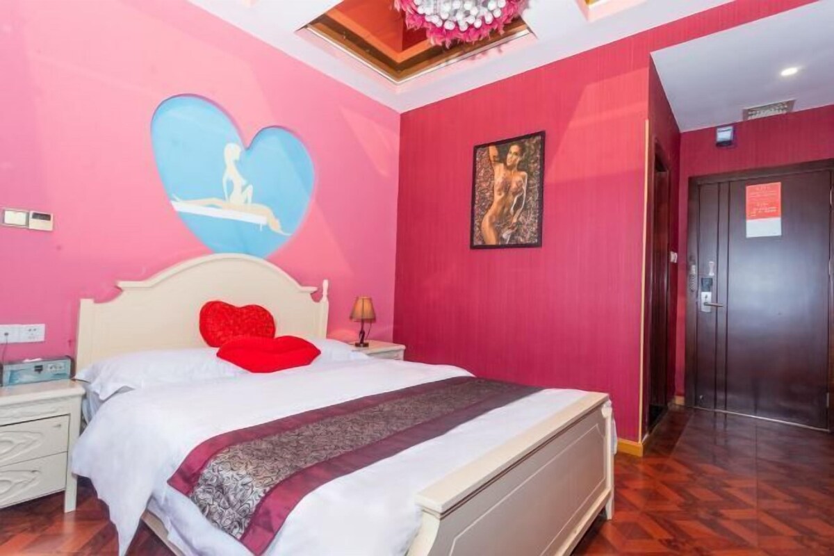 Une chambre à coucher comprenant un lit, une table de chevet, une œuvre d’art murale et une porte.