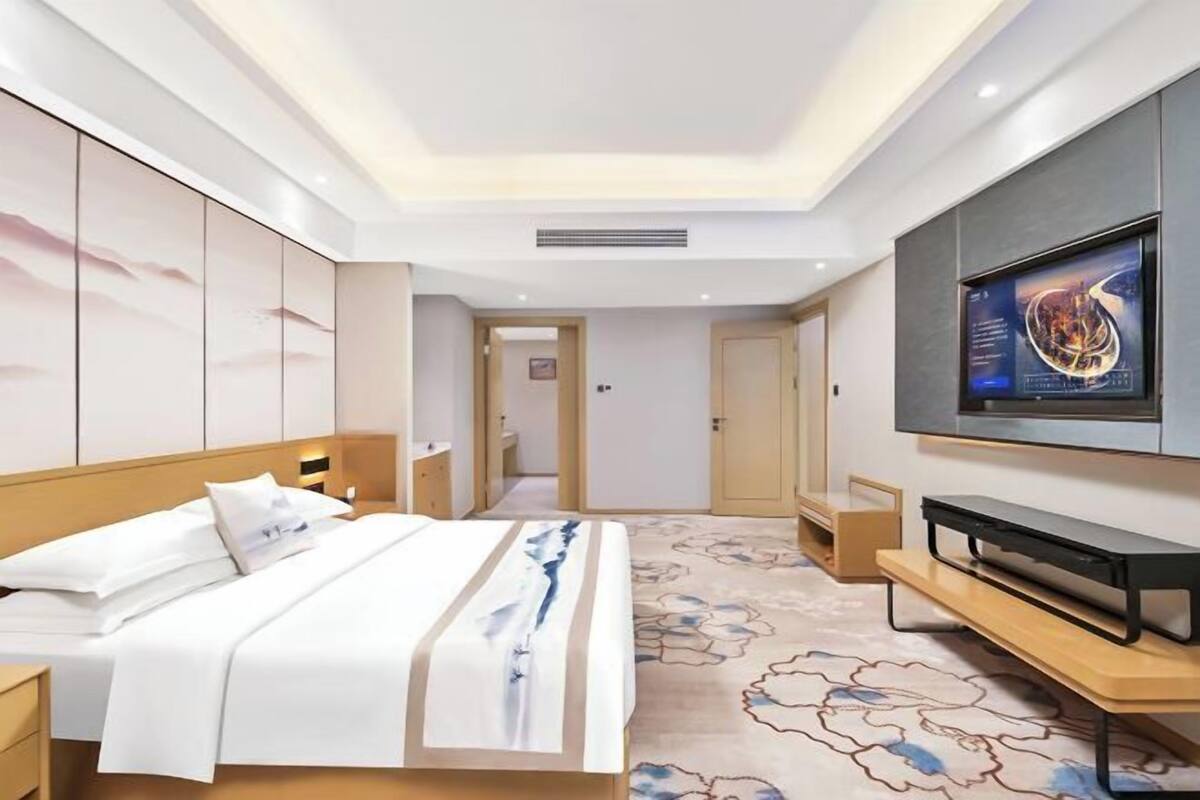 A hotel room with a bed, a TV, a desk, and a wardrobe.