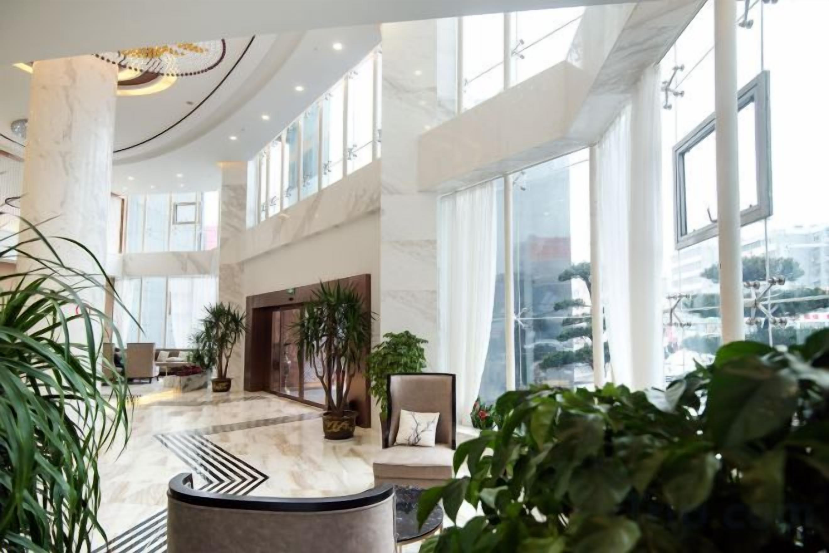 A spacious lobby with high ceilings, large windows, and modern furnishings.