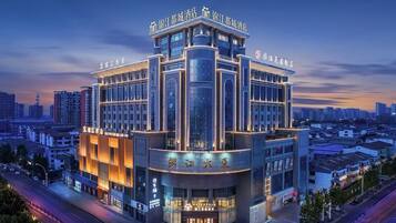 A modern hotel with a corner building design, multiple floors, and illuminated signage.
