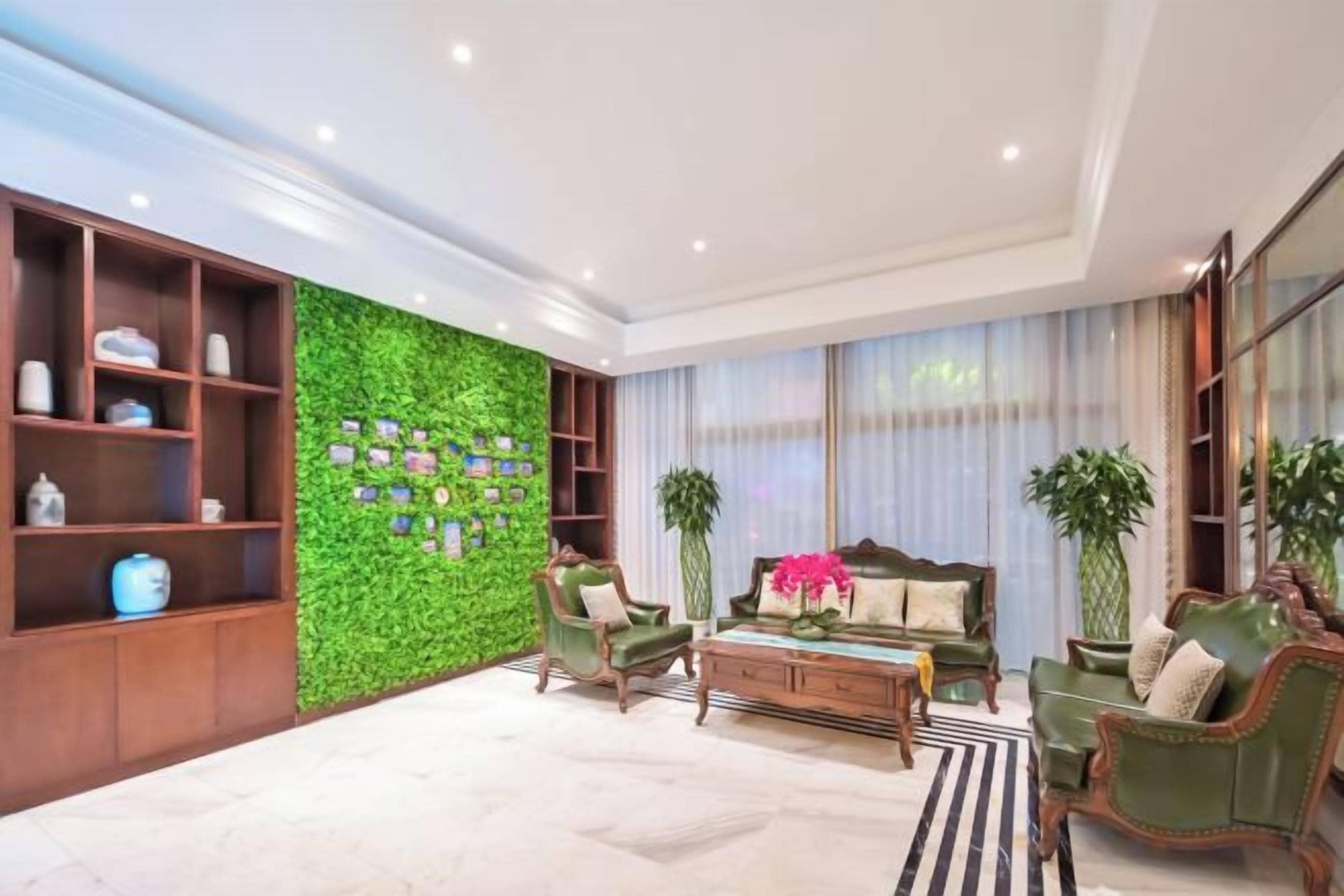 A modern living room with a green wall, wooden shelving, and a sofa set.