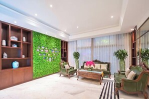 A modern living room with a green wall, wooden shelving, and a sofa set. - Jinjiang Hotel International Hotel (Feng County)
