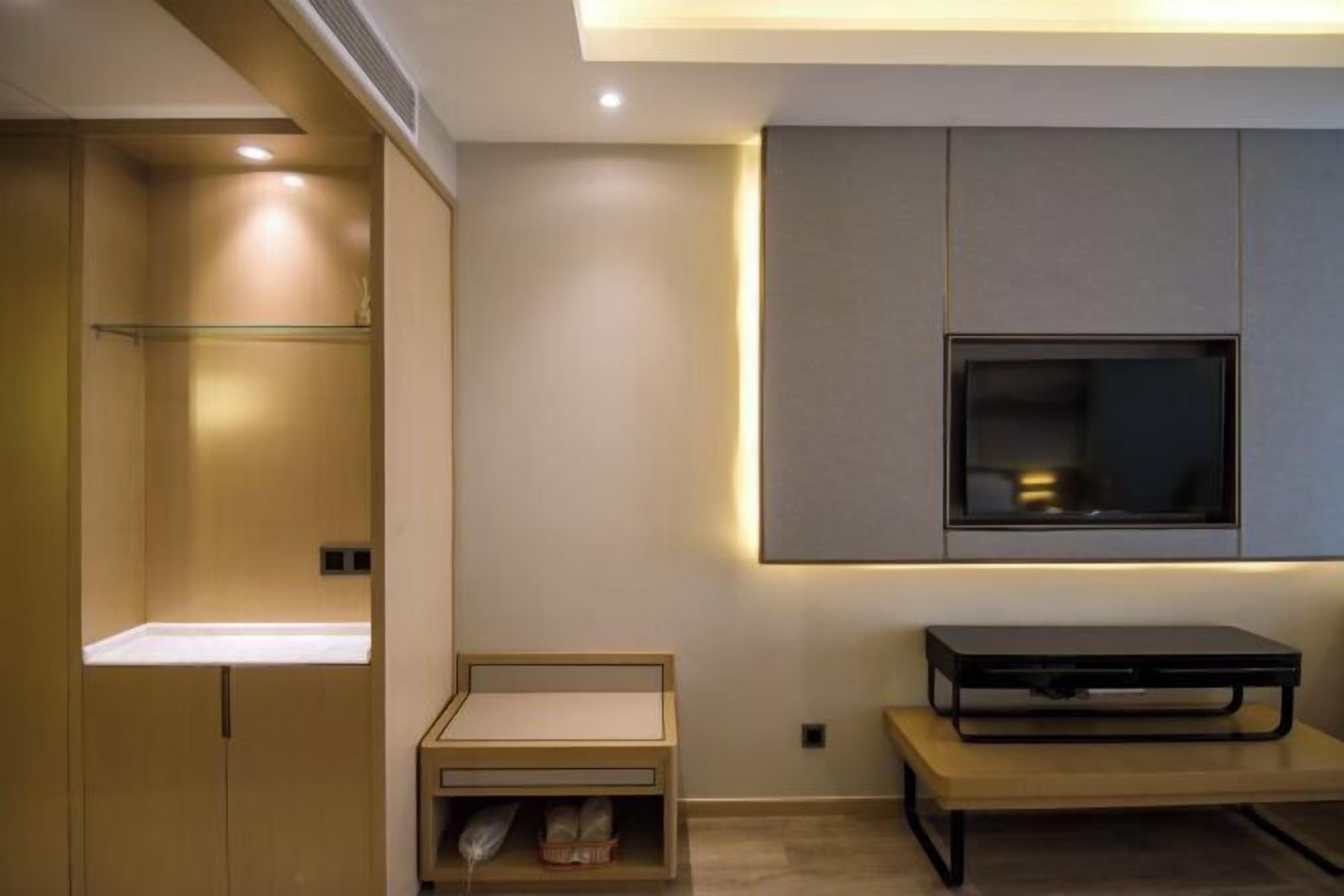 A modern bathroom with a built-in shower, a vanity with a mirror, and a wall-mounted television.