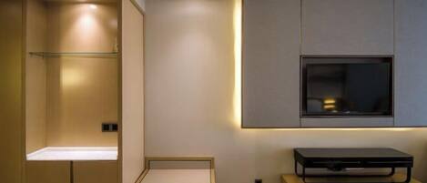 Un baño moderno con ducha integrada, tocador con espejo y televisor de pared.
