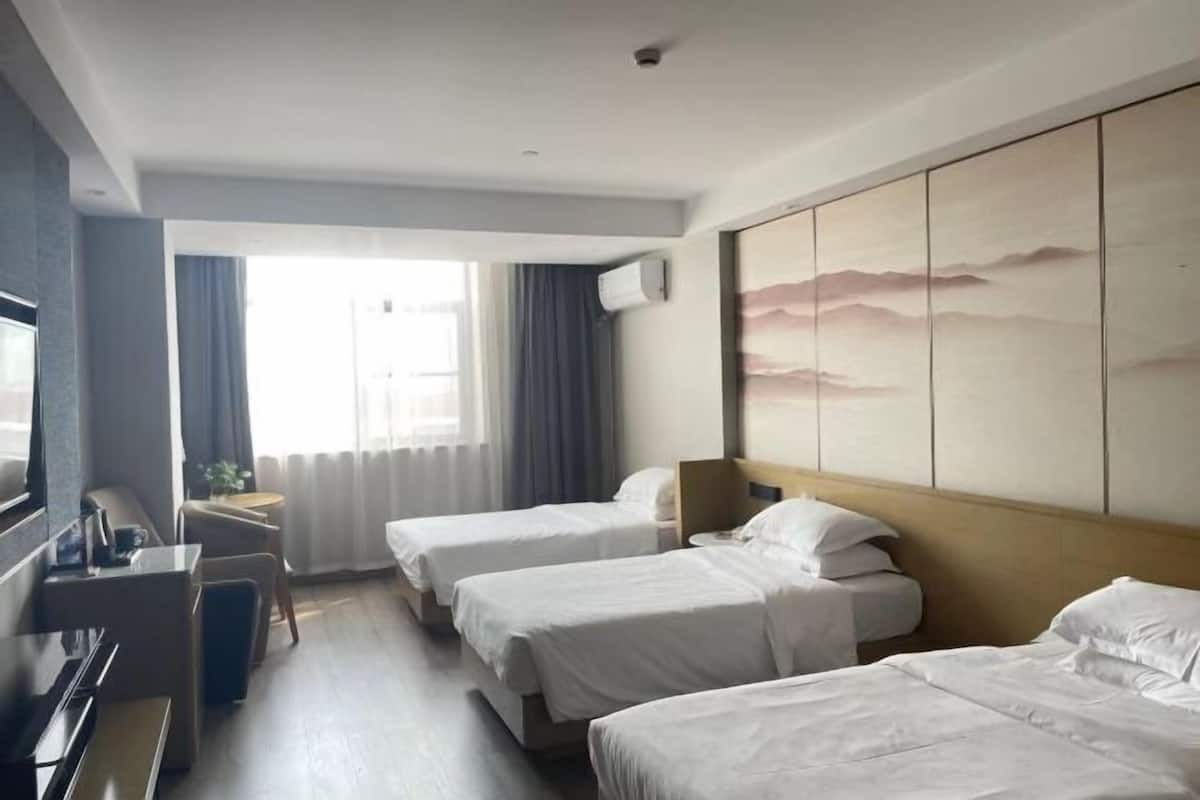 A hotel room with two beds, a desk, a television, and a large window.