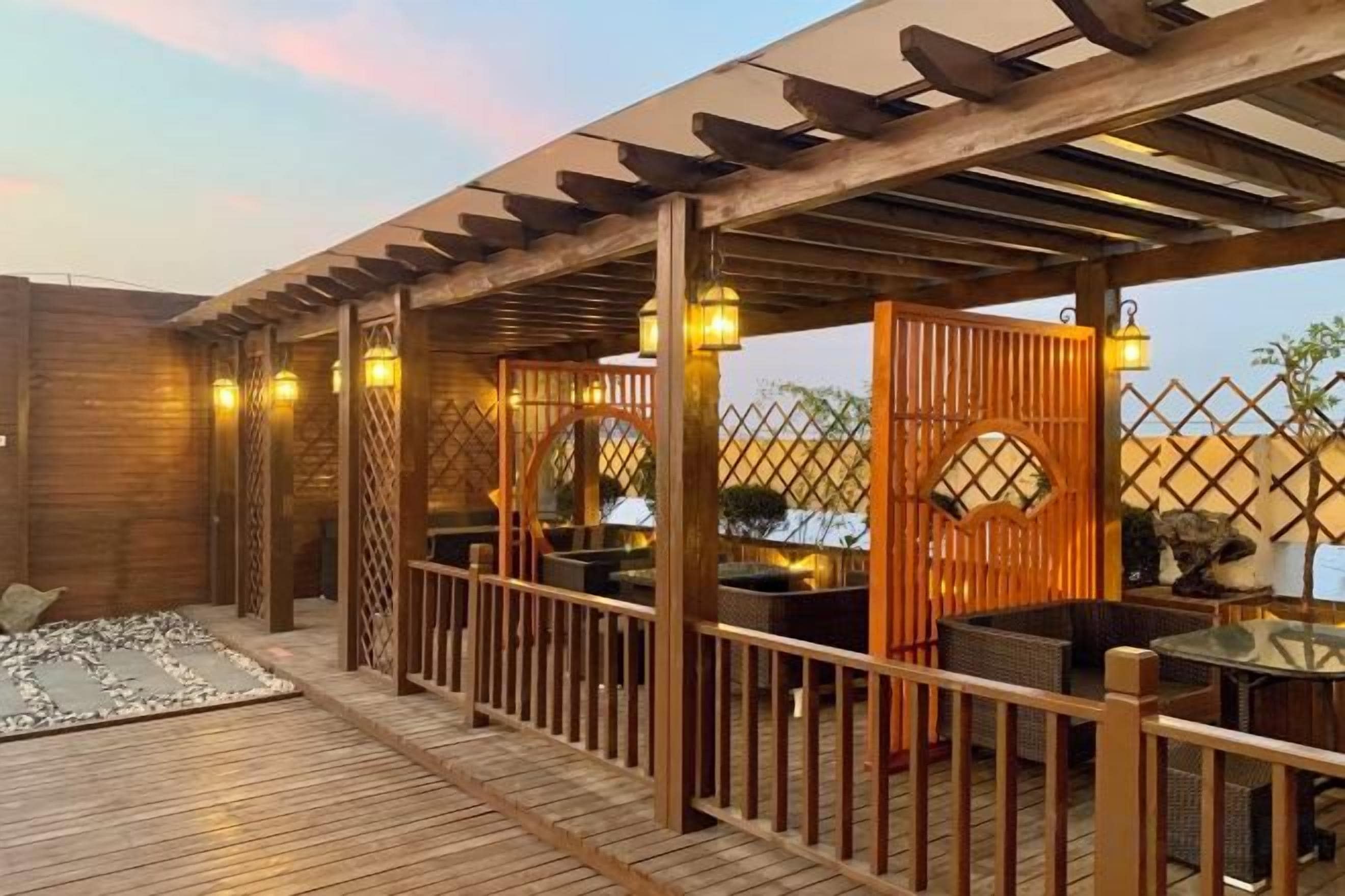 An outdoor wooden deck with a pergola, seating area, and a small water feature.