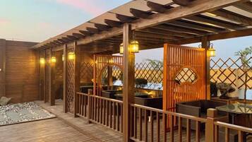 An outdoor wooden deck with a pergola, seating area, and a small water feature.