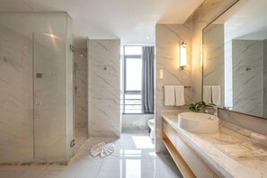 Et moderne badeværelse med et glasafskærmet brusebad, en marmorvask og et stort spejl.