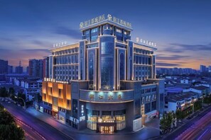 A modern hotel with a prominent corner location, featuring a large glass facade and multiple levels. - Jinjiang Hotel International Hotel (Feng County)