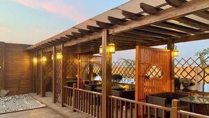 Una terraza de madera con mobiliario exterior y una estructura de pérgola.
