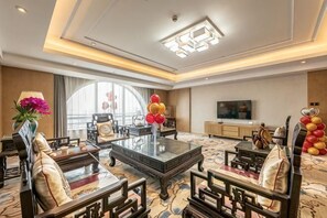 A hotel room with a large window, a flat-screen TV, a sofa, a coffee table, and a decorative vase. - Jinjiang Hotel International Hotel (Feng County)