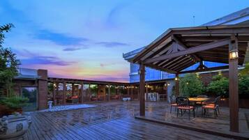 An outdoor wooden deck with a covered seating area and a view of the sky.