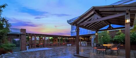 Una terraza de madera al aire libre con un área de estar cubierta y vista al cielo.