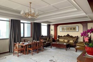 A spacious living room with a chandelier, leather sofas, a dining table with chairs, and a large window with curtains. - Jinjiang Hotel International Hotel (Feng County)