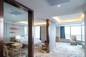 A hotel room with a bed, a desk, a chair, a lamp, and a large window. - Jinjiang Hotel International Hotel (Feng County)