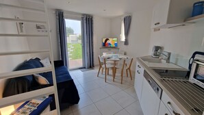 Een ruimtelijk ingerichte leefruimte met een kitchenette, een eethoek en een bank.