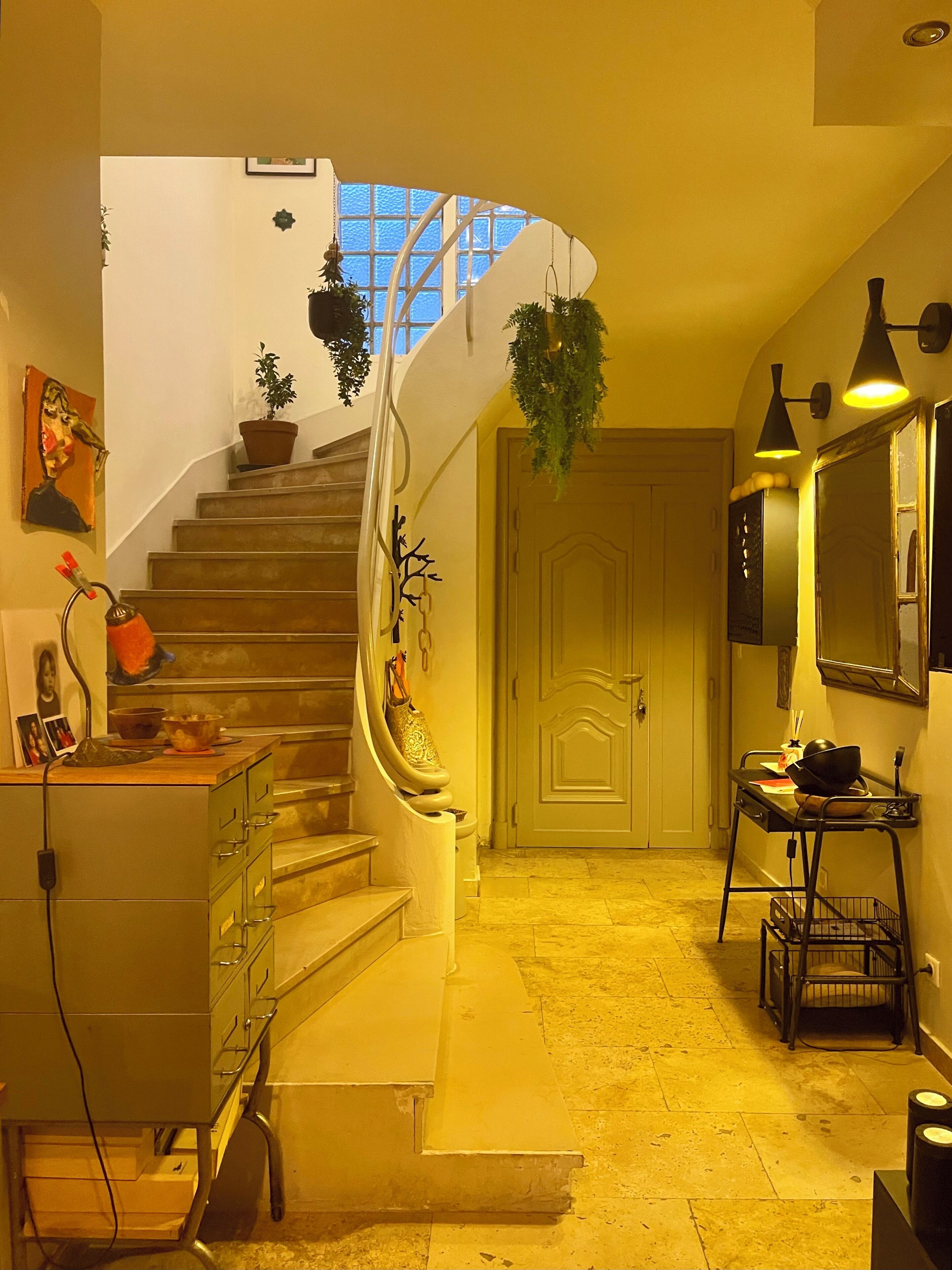A staircase with potted plants, a desk with a chair, and a door leading to another room.