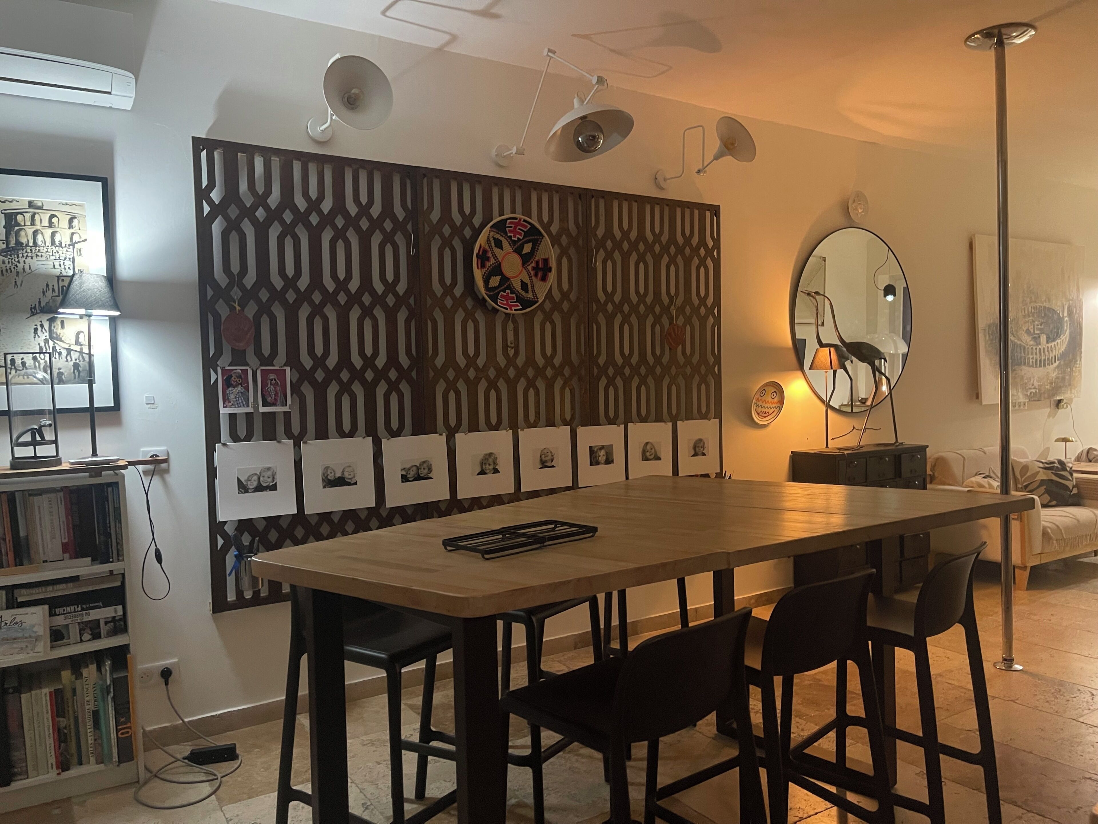 Comedor con mesa de madera, sillas negras, un muro decorado con fotografías y un ventilador de techo.