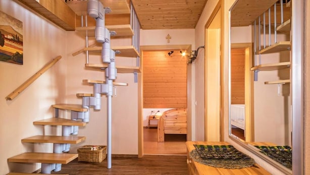 A wooden staircase leading to a room with a bed and a small table. - Ferienhof-Dachsberg Apartment Maisonette (Bermatingen)