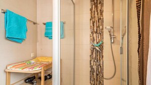 A bathroom with a shower, a bed, and a shelf with a camera. - Ferienhof-Dachsberg Apartment Maisonette (Bermatingen)