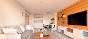A modern living room with a sofa, coffee table, and a TV mounted on a wooden wall.