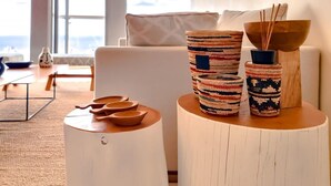Een moderne woonkamer met een witte bank, een ronde houten tafel met decoratieve schalen en diverse gevlochten bakken op een bijzettafeltje.