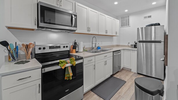 A modern kitchen with white cabinets, stainless steel appliances, and a black countertop.
