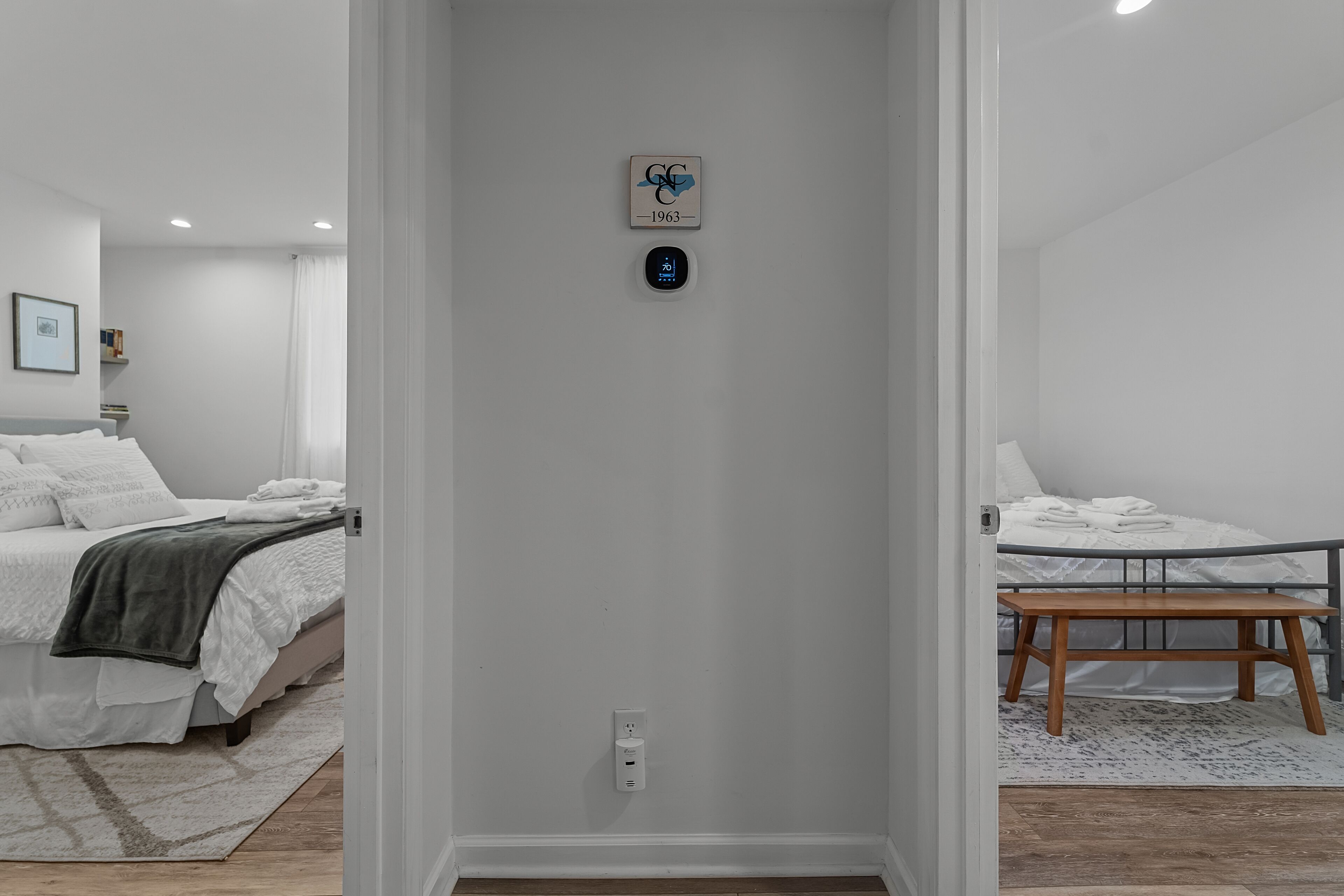 Habitació d'hotel amb llit, taula de nit i panell de control fixat a la paret.