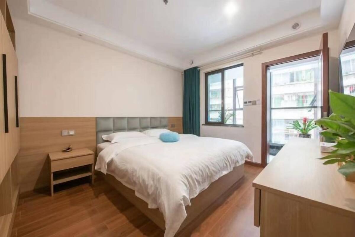 A modern bedroom with a bed, bedside table, and a window with curtains.