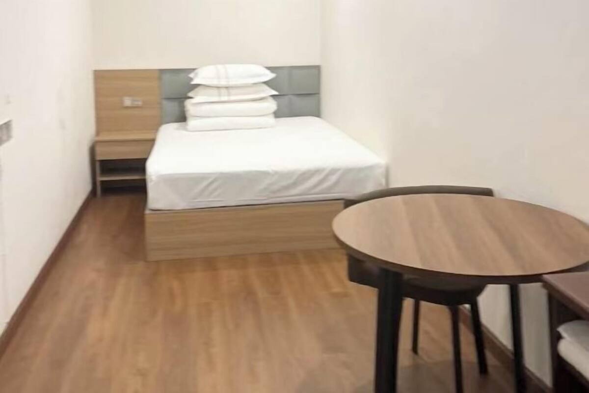 A compact hotel room with a bed, bedside table, and a small round table.