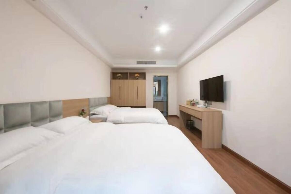 A hotel room with two beds, a desk, a TV, and a wardrobe.