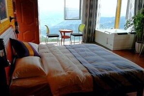 Une chambre à coucher avec un lit, une petite table et des chaises, et une vue sur l’extérieur.