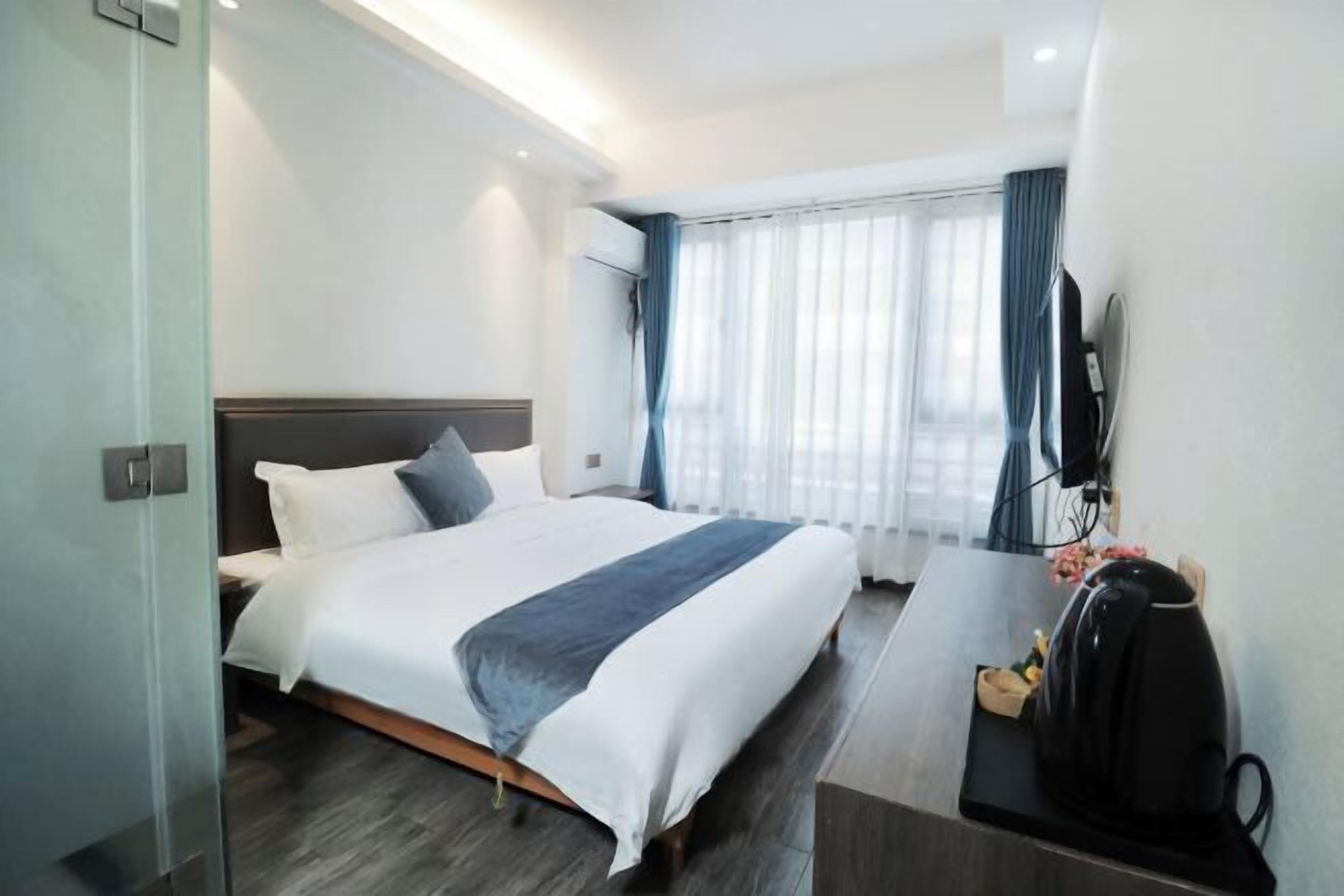 Hotellihuone, jossa on sänky, työpöytä, vedenkeitin ja televisio.