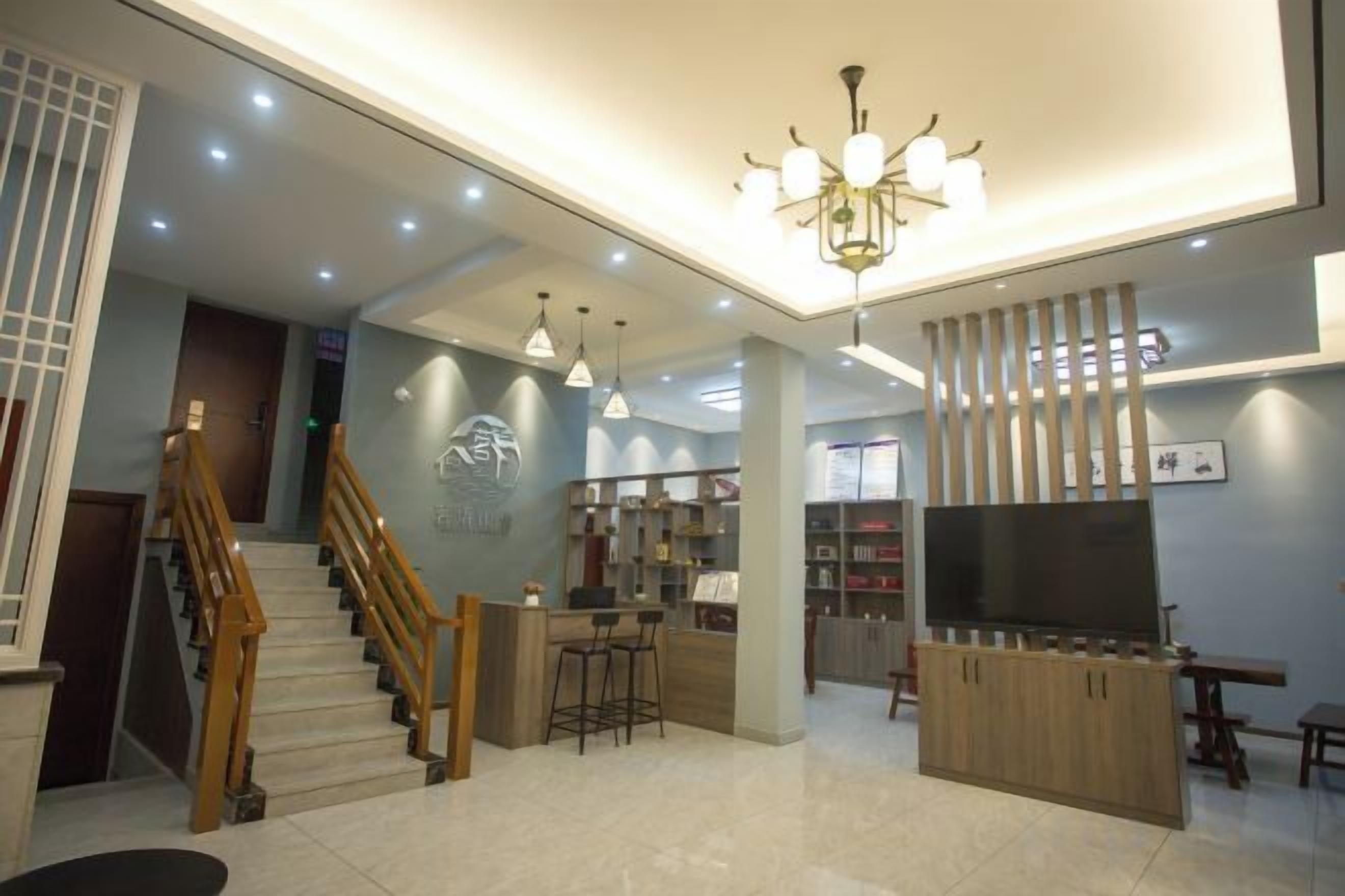 A modern hotel lobby with a staircase, bar area, and seating.