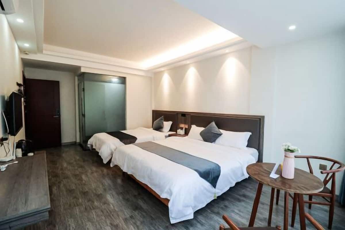 A hotel room with two beds, a desk, and a small table with a chair.
