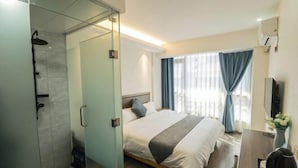 A hotel room with a bed, a desk, a TV, a shower, and a window with curtains. - Mingyu Shanshe Hostel (Wuyishan)